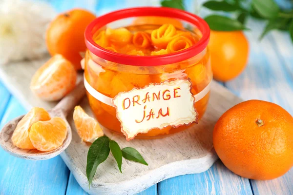 Sinaasappeljam met schil en mandarijnen, op blauwe houten tafel — Stockfoto