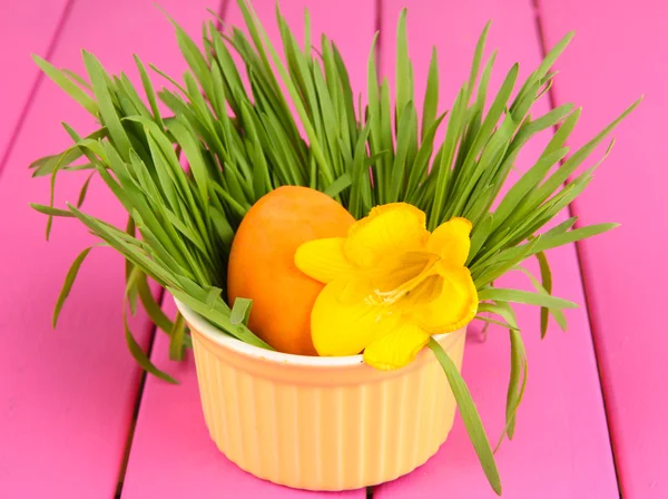 Osterei in Schüssel mit Gras auf rosa Holztisch in Großaufnahme — Stockfoto