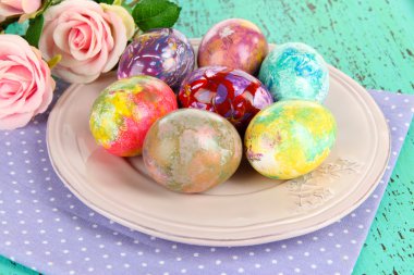 peçete ve ahşap masa çiçekleri ile plaka üzerinde Paskalya yortusu yumurta