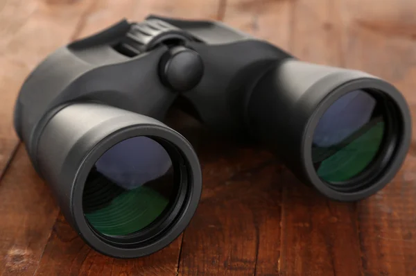 Black modern binoculars on wooden background — Stock Photo, Image