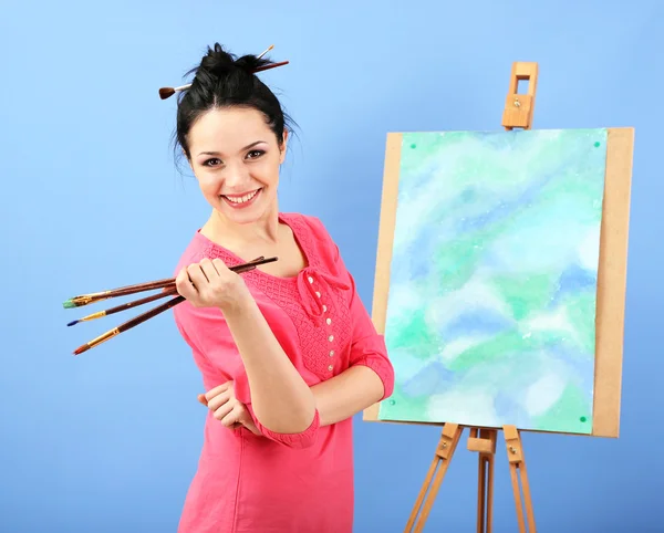 Beautiful young woman painter at work, on color background — Stock Photo, Image