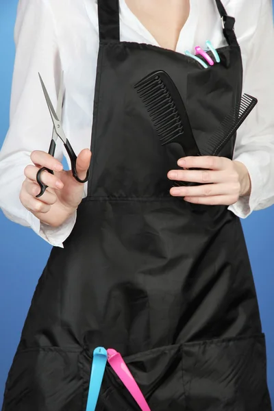 Cabeleireiro em uniforme com ferramentas de trabalho, em fundo de cor — Fotografia de Stock