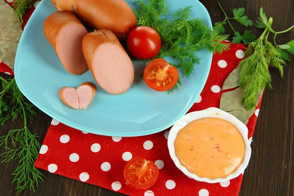 Embutidos, verduras, tomate en plato sobre mesa de madera — Foto de Stock