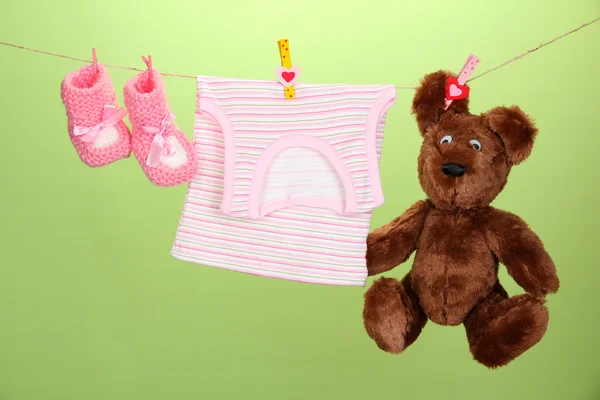Ropa de bebé colgada en el tendedero, sobre fondo de color — Foto de Stock