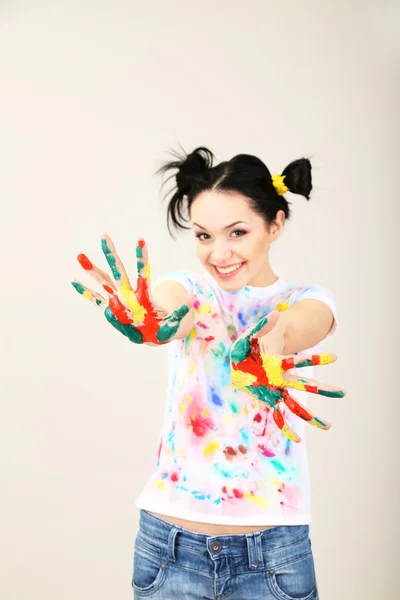 Junge hübsche Malerin mit Händen in Farbe, auf grauem Hintergrund — Stockfoto