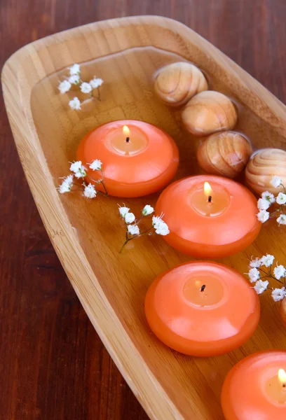 Beautiful candles in water on wooden table close-up — Stock Photo, Image