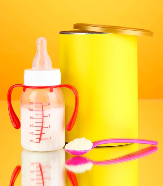 Botol dengan susu dan makanan untuk bayi dengan latar belakang oranye — Stok Foto