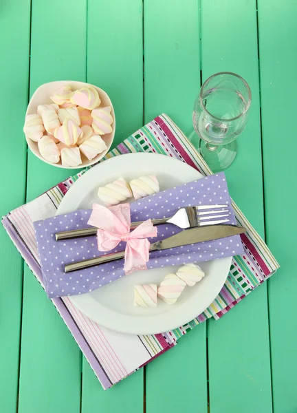 Tischdekoration in violetten und weißen Tönen auf farbigem Holzhintergrund Stockfoto