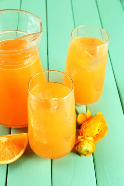 Brýle a džbánek pomerančového džusu na modré dřevěné pozadí — Stock fotografie