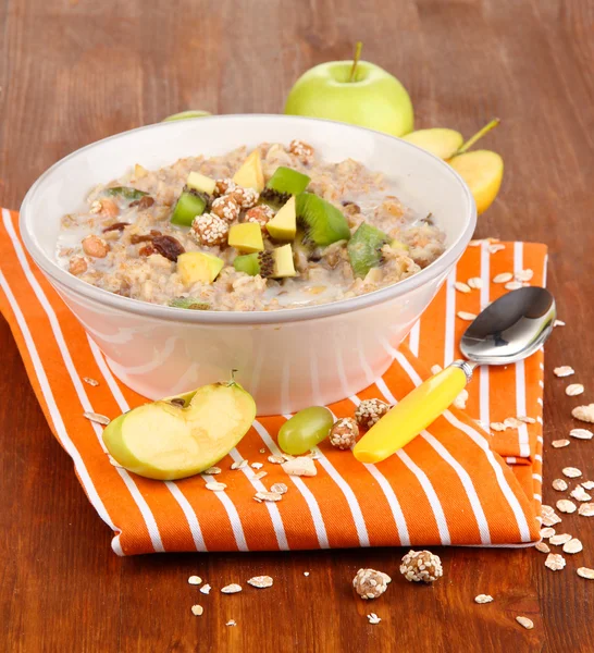 Useful oatmeal in bowl with fruit on wooden table close-up — Stock Photo, Image