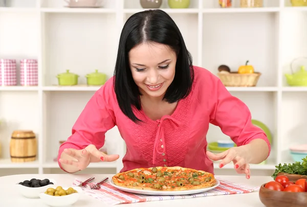 Beautiful girl wants to eat delicious pizza on kitchen background — Stock Photo, Image