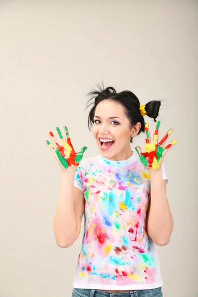 Junge hübsche Malerin mit Händen in Farbe, auf grauem Hintergrund — Stockfoto