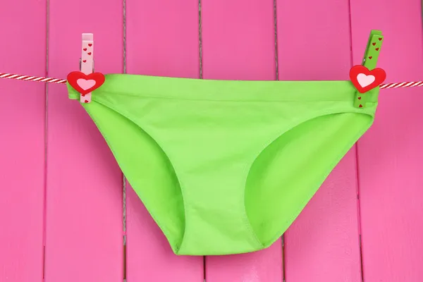 Womans panties hanging on a clothesline, on pink wooden background — Stock Photo, Image