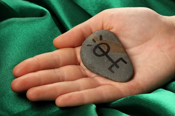 Fortune telling with symbols on stone in hand on green fabric background — Stock Photo, Image