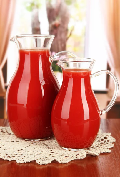 Tomato juice in pitchers on table in room — Stock Photo, Image