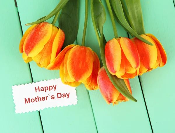 Schöne orange Tulpen auf farbigem Holzhintergrund — Stockfoto