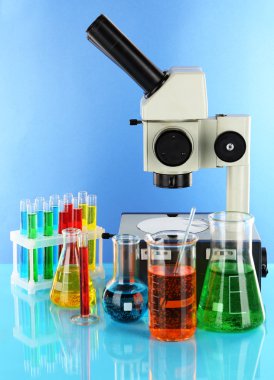 test tüpleri ile renkli sıvılar ve mikroskop mavi zemin üzerine