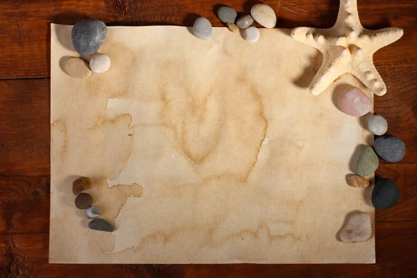 Vecchia carta, stelle marine e pietre su tavolo di legno — Foto Stock