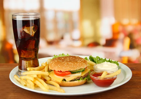 Smakelijke cheeseburger met gebakken aardappelen en koud drankje, op lichte achtergrond — Stockfoto