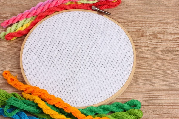 The embroidery hoop with canvas and bright sewing threads for embroidery in the table — Stock Photo, Image