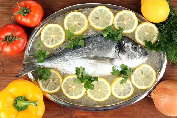 Fresh fish of dorado on tray with lemon and parsley on wooden table — Stock Photo, Image