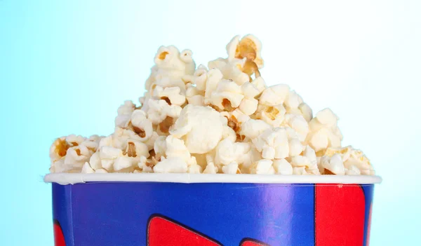 Bucket with popcorn on blue — Stock Photo, Image