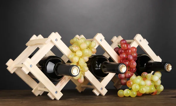 Botellas de vino colocadas sobre soporte de madera sobre fondo gris — Foto de Stock