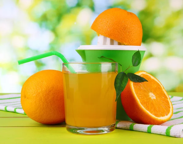 Presse agrumes, verre de jus et oranges mûres sur table en bois blanc — Photo