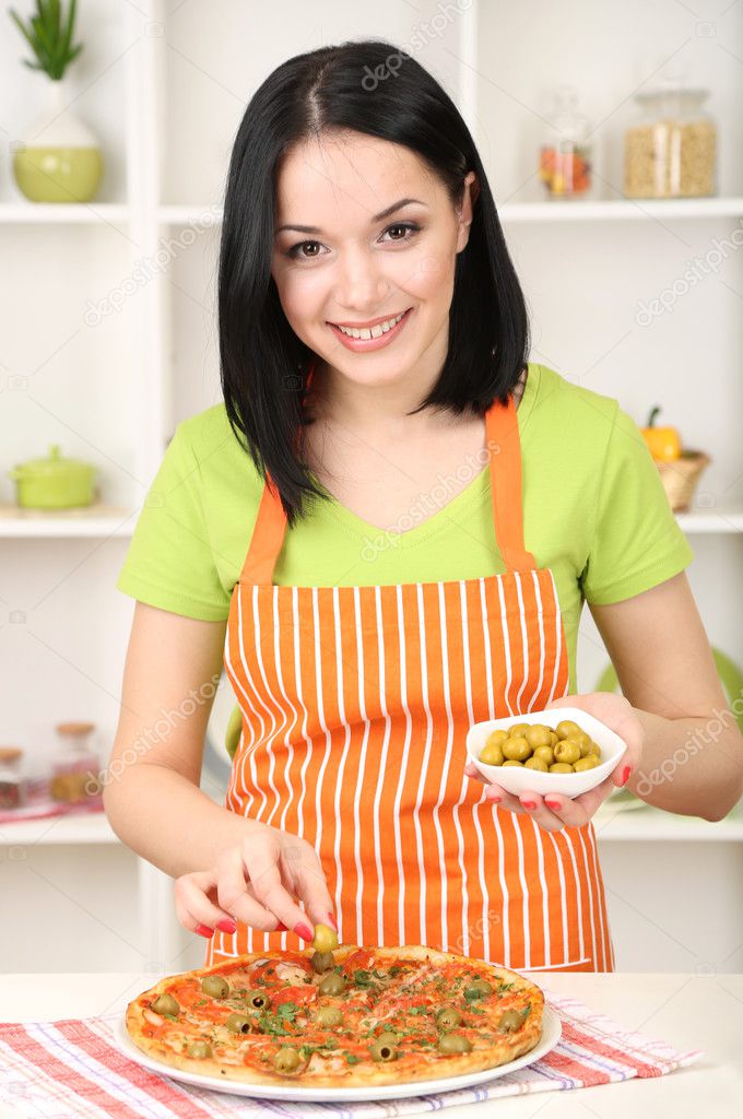 Girl housewife with delicious pizza on kitchen background