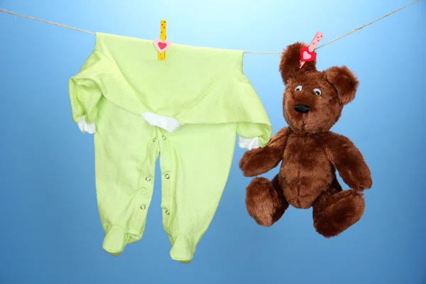 Dětské oblečení na prádelní šňůru, na modrém pozadí — Stock fotografie