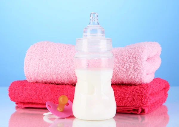 Flasche für Milch mit Handtüchern und Brustwarzen auf blauem Hintergrund — Stockfoto