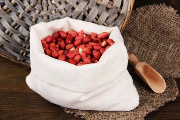 Peanuts in sack on wooden background — Stock Photo, Image