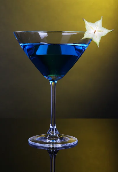 Blue cocktail in martini glass on dark yellow background — Stock Photo, Image