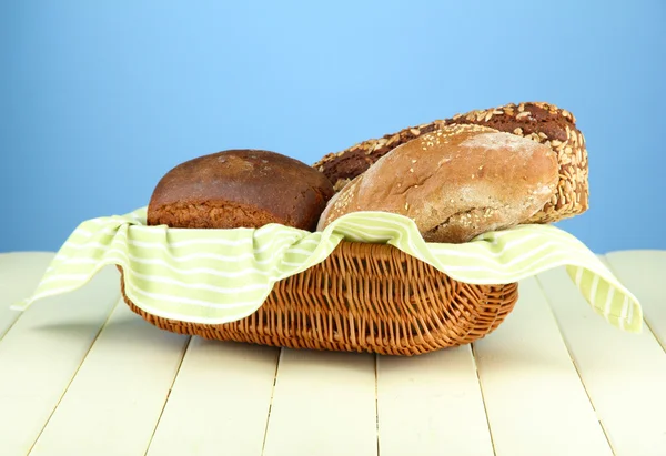 Pane in cesto di vimini, su tavolo di legno, su sfondo a colori — Foto Stock