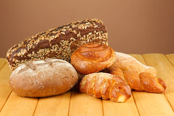 Composition with bread and rolls on wooden table, on color background — Stock Photo, Image