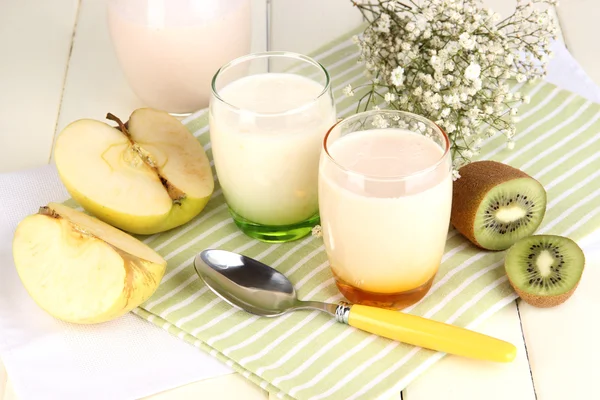 Delicious yogurts with fruits in glasses on wooden table close-up — Stock Photo, Image