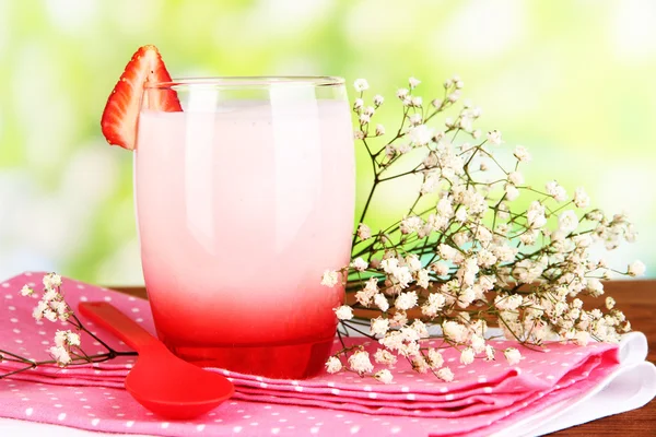 Delicious strawberry yogurt in glass on wooden table on natural background — Stock Photo, Image