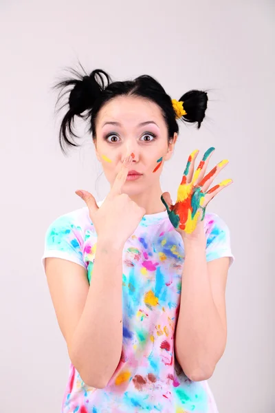 Junge hübsche Malerin mit Händen in Farbe, auf grauem Hintergrund — Stockfoto