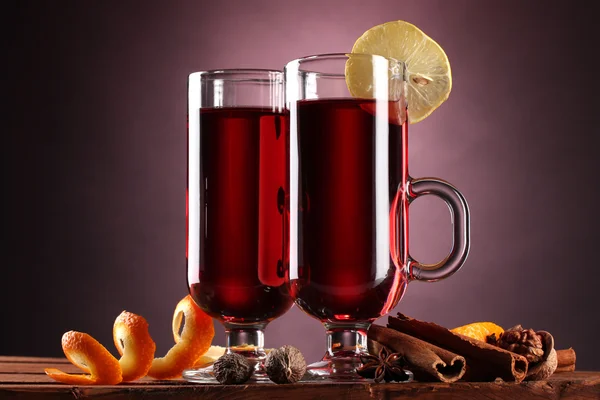 Mulled wine in the glasses, spice and lemon on purple background — Stock Photo, Image