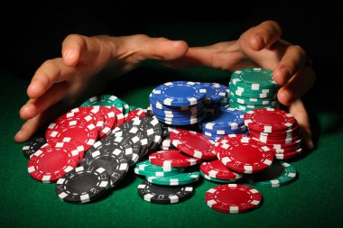 Poker fişleri ve yeşil masa üstündeki elleri