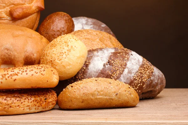 Delicioso pão na mesa de madeira no fundo marrom — Fotografia de Stock