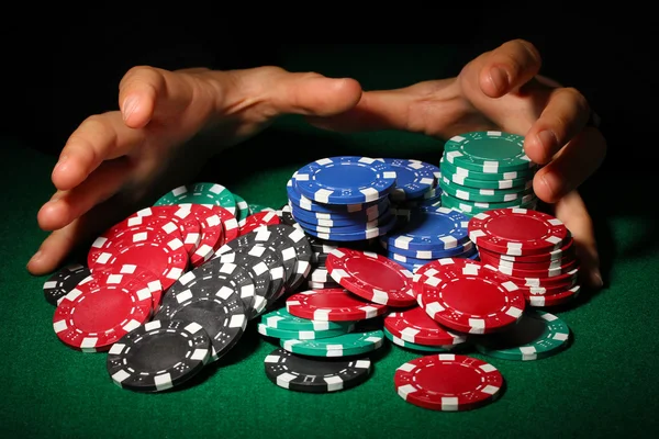 Poker žetony a ruce nad ní na zeleném stole — Stock fotografie