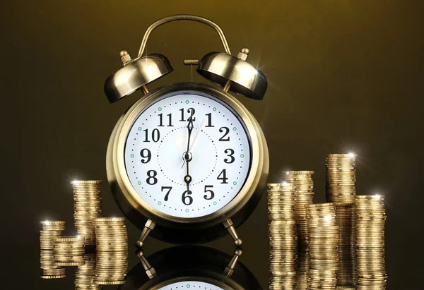 Reloj despertador con monedas sobre fondo oscuro — Foto de Stock