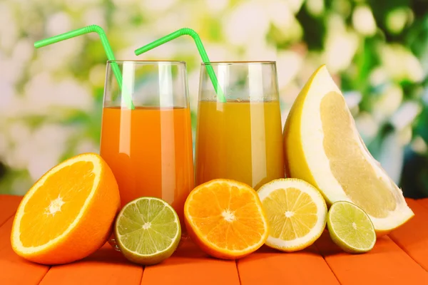 Lots ripe citrus with juices on wooden table on natural background — Stock Photo, Image