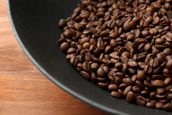 Black wok pan with coffee beans on wooden table, close up — Stock Photo, Image