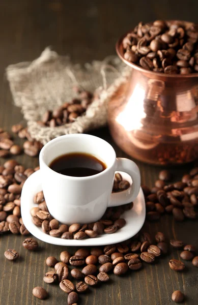 Cup of coffee and pot on wooden background — Stock Photo, Image