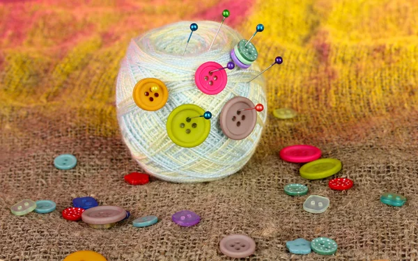 Ball of thread in the buttons on a colorful background — Stock Photo, Image