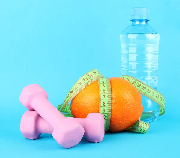 Orange with measuring tape, dumbbells and bottle of water, on color background — Stock Photo, Image