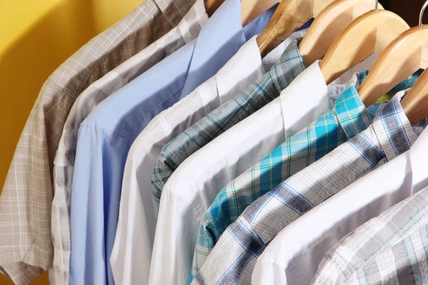 Men's shirts on hangers on yellow background — Stock Photo, Image