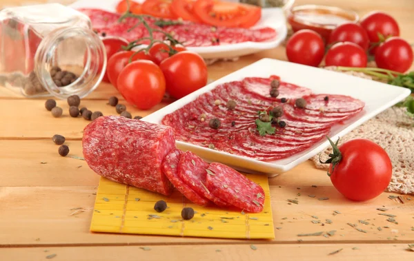 Salame saboroso em pratos em mesa de madeira close-up — Fotografia de Stock